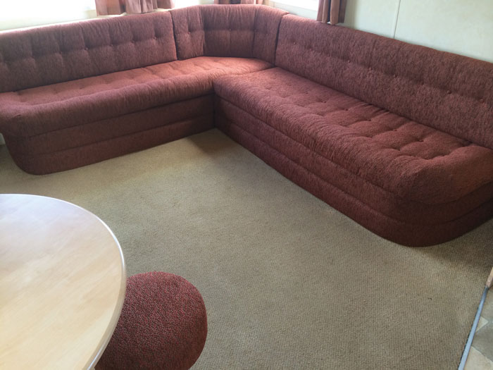 A static caravan corner seating area with re-upholstered seat cushions and kick boards and a re-covered stool